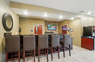 a large dining room with a bar with leather chairs at Cobblestone Hotel & Suites - Russells Point at Indian Lake in Russells Point