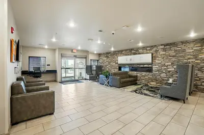 a large lobby with couches and a stone wall at Cobblestone Hotel & Suites - Russells Point at Indian Lake in Russells Point