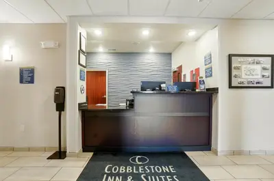 a lobby with a reception desk in a building at Cobblestone Hotel & Suites - Russells Point at Indian Lake in Russells Point