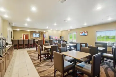 a restaurant with tables and chairs and a bar at Cobblestone Hotel & Suites - Russells Point at Indian Lake in Russells Point