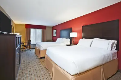 two beds in a hotel room with red walls at Holiday Inn Express & Suites Springfield by IHG in Springfield