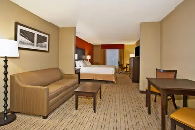 a hotel room with a bed and a living room at Holiday Inn Express & Suites Springfield by IHG in Springfield