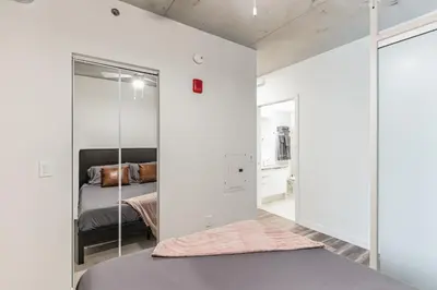 a bedroom with white walls and a bed with a mirror at DT Delight Downtown Living One-bedroom Endless Access in Cleveland