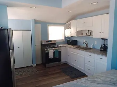 a kitchen with white cabinets and a stove and a window at Rye Beach Retreat in Huron