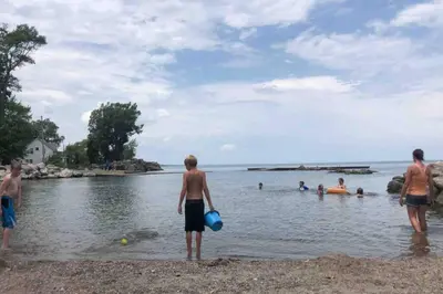a group of people standing on a beach in the water at Rye Beach Retreat in Huron