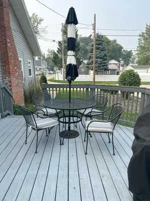 a table and chairs with an umbrella on a deck at Rye Beach Retreat in Huron