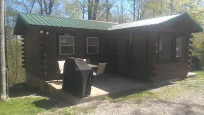 a log cabin with a table and a grill at Two Creeks Camp in Athens