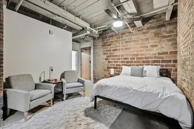 a brick walled bedroom with a bed and two chairs at 2125 Superior Living in Cleveland