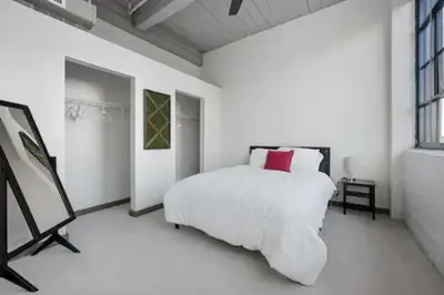 a white bedroom with a bed with a red pillow at 2125 Superior Living in Cleveland