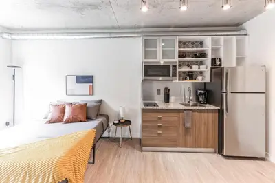 a bedroom with a bed and a kitchen with a refrigerator at Urban Elegance Studio Oasis Prime Location in Cleveland