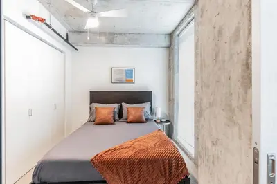 a bedroom with a bed with an orange blanket at Sleek downtown Cleveland apartment in Cleveland