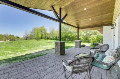 an outdoor patio with chairs and a wooden roof at Dry Ridge Farmhouse with Hot Tub and Game Room! in Dry Ridge