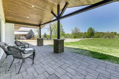 an outdoor patio with chairs and a wooden roof at Dry Ridge Farmhouse with Hot Tub and Game Room! in Dry Ridge