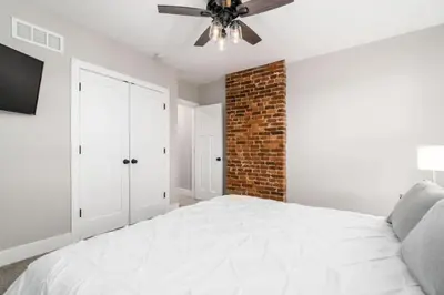 a bedroom with a white bed and a brick wall at Entire Home Private Parking Fenced Yard in Columbus