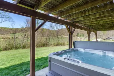 a hot tub sitting under a pergola at Spacious Cabin Near Hocking Hills and Caves with Hot Tub and Firepit in Laurelville