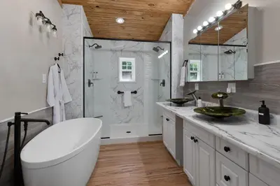 a white bathroom with a shower and a sink at Spacious Cabin Near Hocking Hills and Caves with Hot Tub and Firepit in Laurelville