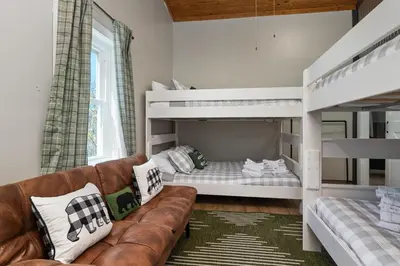 a living room with bunk beds and a couch at Spacious Cabin Near Hocking Hills and Caves with Hot Tub and Firepit in Laurelville