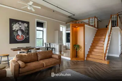 a living room with a couch and a staircase at Above Coffee Shop, Cincy Hilltop Apt, City Views! in Cincinnati