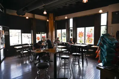 a group of people sitting at tables in a restaurant at Above Coffee Shop, Cincy Hilltop Apt, City Views! in Cincinnati