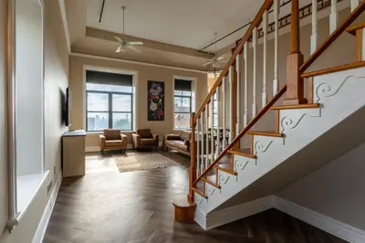 a living room with a staircase and a living room with chairs at Above Coffee Shop, Cincy Hilltop Apt, City Views! in Cincinnati