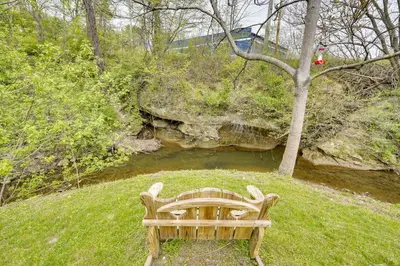 a wooden bench sitting in the grass next to a river at Pet-Friendly Zanesville Haven with Game Room! in Zanesville