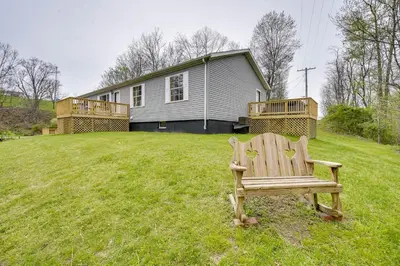 a wooden bench sitting in the grass in front of a house at Pet-Friendly Zanesville Haven with Game Room! in Zanesville