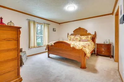 a bedroom with a wooden bed and a dresser at Serene Zanesville Getaway Hot Tub, 2 Decks! in Zanesville