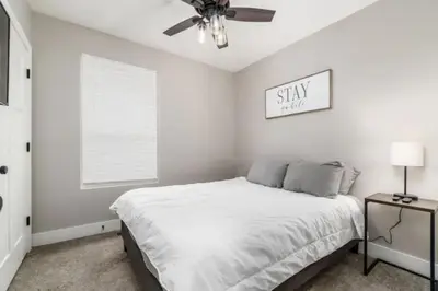 a white bedroom with a bed and a ceiling fan at 2 homes side by side downtown with fenced yard and hot tub in Columbus