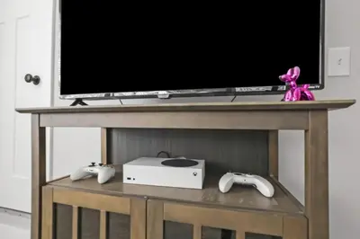 a television on a table with two video game controllers at 2 homes side by side downtown with fenced yard and hot tub in Columbus