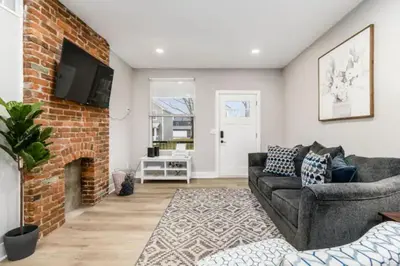 a living room with a couch and a brick fireplace at 2 homes side by side downtown with fenced yard and hot tub in Columbus