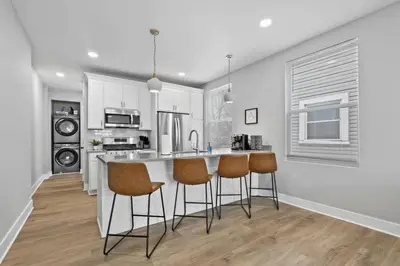 a kitchen with white cabinets and a bar with stools at Massive home downtown with Hot Tub in Columbus