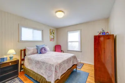 a bedroom with a bed and a dresser and two windows at Charming Home - 4 Mi to Euclid Creek Reservation in South Euclid