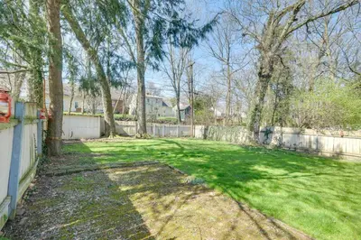 a yard with a fence and some trees and grass at Cleveland Heights Home with Sunroom Park Across St! in Cleveland Heights