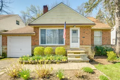 a brick house with an american flag in front of it at Cleveland Heights Home with Sunroom Park Across St! in Cleveland Heights