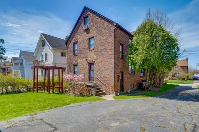 an old brick house with a playground in the yard at Trendy South Euclid Apt - 5 Mi to Cleveland Clinic in South Euclid