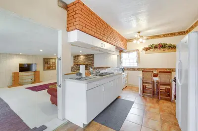 a kitchen with white cabinets and a brick wall at Spacious Studio - 5 Mi to MGM Northfield Park! in Maple Heights