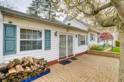 a white house with blue windows and a pile of logs at Spacious Studio - 5 Mi to MGM Northfield Park! in Maple Heights