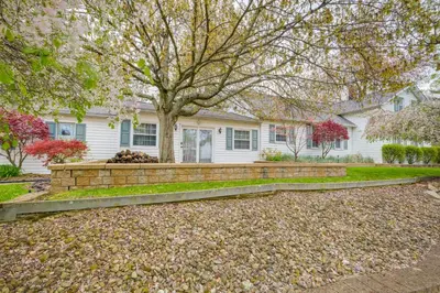 a home with a stone retaining wall and a tree at Spacious Studio - 5 Mi to MGM Northfield Park! in Maple Heights