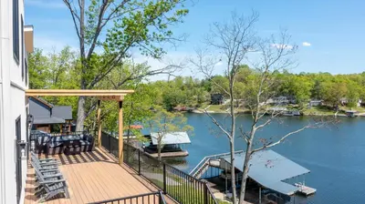 a house with a deck with a boat in the water at Lakeside, Water-view, 7 miles to Ark, 4BR for 14 in Williamstown