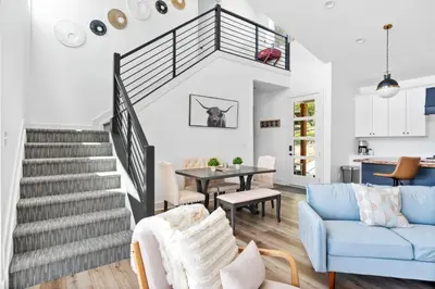 a living room with a staircase and a table at Lakeside, Water-view, 7 miles to Ark, 4BR for 14 in Williamstown