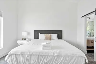a white bedroom with a large bed with white sheets at Lakeside, Water-view, 7 miles to Ark, 4BR for 14 in Williamstown