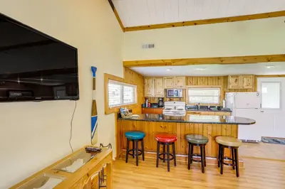a kitchen with wooden cabinets and bar stools at Waterfront Port Clinton Cottage with Fire Pit! in Port Clinton