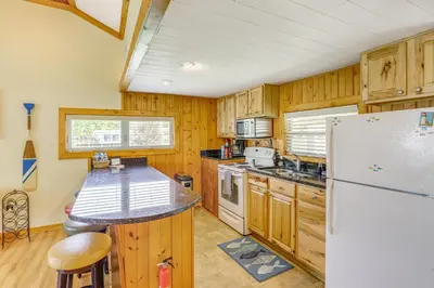 a kitchen with wooden cabinets and a refrigerator at Waterfront Port Clinton Cottage with Fire Pit! in Port Clinton
