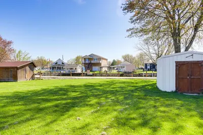 a large grass field with houses in the background at Waterfront Port Clinton Cottage with Fire Pit! in Port Clinton