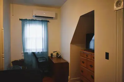 a bedroom with a dresser and a window with a television at Downtown Lima 1 Bdrm Haven! in Lima