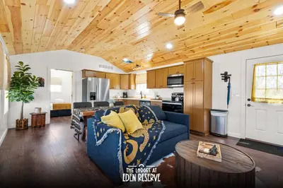 a living room with a blue couch and a kitchen at The Lodges at Eden Reserve - Pet Friendly Cabins Near Ark in Williamstown
