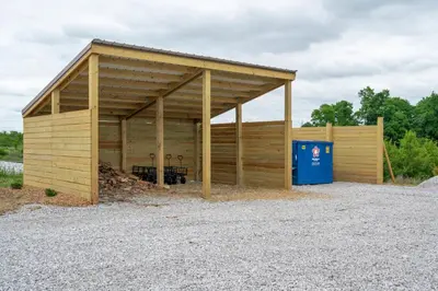 a large woodenshed with a blue recycling container at The Lodges at Eden Reserve - Pet Friendly Cabins Near Ark in Williamstown