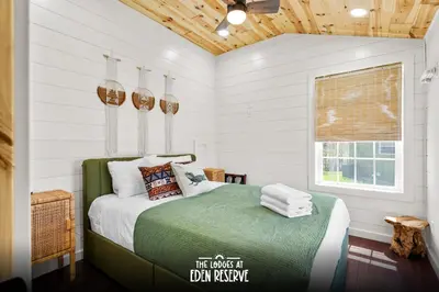 a bedroom with a bed with white walls and a window at Block of 5 Lodges at Eden Reserve - For Groups in Williamstown