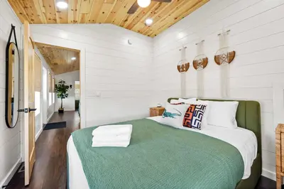 a bedroom with a large bed with a green blanket at Block of 5 Lodges at Eden Reserve - For Groups in Williamstown