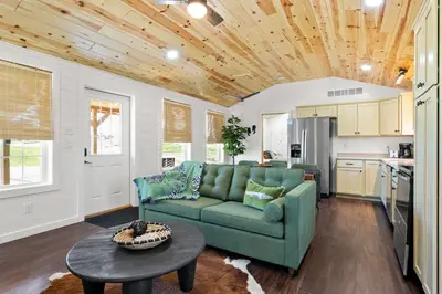 a living room with a green couch and a table at Block of 5 Lodges at Eden Reserve - For Groups in Williamstown